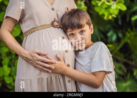 Un moment réconfortant capturé dans le parc alors qu'une femme enceinte après 40 partage un lien spécial avec son fils adolescent, embrassant la beauté de la mère Banque D'Images