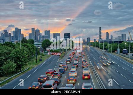 Le soleil au coucher du soleil a traversé un épais nuage sombre au-dessus des Docklands où le trafic intense du soir rampant sur l'A102 sud de Londres Angleterre Royaume-Uni Banque D'Images