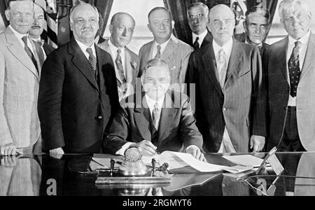 Herbert Hoover signe le Farm relief Bill, avec neuf autres hommes debout à côté et derrière lui ca. 1929 Banque D'Images