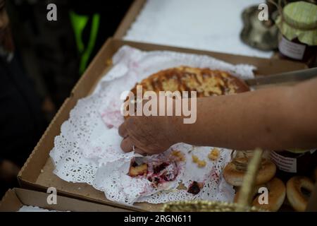 Coupe la tarte à la main. Bonbons russes. Pâtisseries de grand-mère. Nourriture délicieuse. Détails du produit à base de farine. Couteau dans la main du cuisinier. Banque D'Images