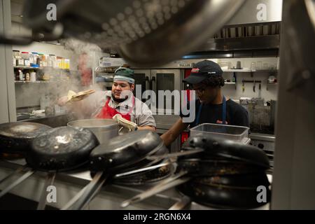 Reportage : SNAP emploi et formation au café Reconcile à la Nouvelle-Orléans LA (février 2023) - Right, un stagiaire de 20 ans au café Reconcile, prépare de la nourriture sous la supervision d'un formateur défenseur de la cuisine, de la pâtisserie et du service au café Reconcile, avant l'ouverture du restaurant à la Nouvelle-Orléans, la., 16 février 2023. Banque D'Images