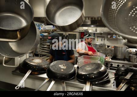 Reportage : SNAP emploi et formation au café Reconcile à la Nouvelle-Orléans LA (février 2023) - à gauche, un stagiaire de 20 ans au café Reconcile, prépare de la nourriture sous la direction d'un formateur défenseur de la cuisine, de la pâtisserie et du service au café Reconcile, avant l'ouverture du restaurant à la Nouvelle-Orléans, la., 16 février 2023. Banque D'Images