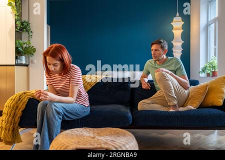 L'homme et la femme sont assis séparément, ne communiquant pas. Couple marié après une vive querelle émotionnelle. Banque D'Images