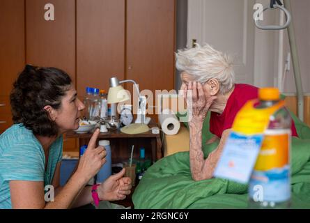 Berlin, Allemagne. 31 juillet 2023. L’aidante Ramona Rössner parle à sa patiente, Brigitte Richter, âgée de 97 ans, qui a besoin de soins, lors d’une visite à domicile. Crédit : Monika Skolimowska/dpa/Alamy Live News Banque D'Images