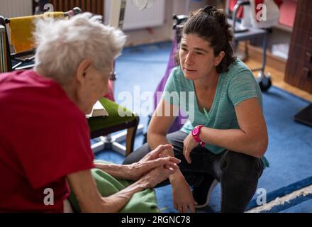 Berlin, Allemagne. 31 juillet 2023. La soignante Ramona Rössner écoute sa patiente, Brigitte Richter, âgée de 97 ans, qui a besoin de soins, lors d’une visite à domicile. Crédit : Monika Skolimowska/dpa/Alamy Live News Banque D'Images