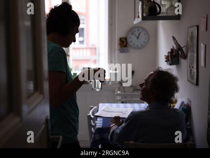 Berlin, Allemagne. 31 juillet 2023. L’infirmière Ramona Rössner remet un verre d’eau à son patient Andreas Seltzer, qui a besoin de soins, lors d’une visite à domicile. Crédit : Monika Skolimowska/dpa/Alamy Live News Banque D'Images