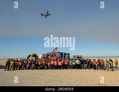 Reportage : Boeing orbital Flight Test-2 Landing (mai 2022) - la NASA et les équipes Boeing posent pour une photo de groupe alors qu'un avion HC-130J Hercules de l'USAF du 79e escadron de sauvetage vole au-dessus du vaisseau spatial Boeing CST-100 Starliner après que Starliner a atterri au Space Harbor du White Sands missile Range, le mercredi 25 mai 2022, au Nouveau-Mexique. Banque D'Images