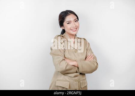 Une jeune femme asiatique en uniforme kaki brun montrant un geste confiant en pliant les bras. Fonctionnaire indonésien. Banque D'Images