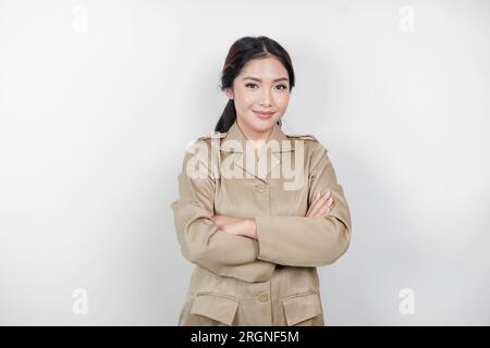 Une jeune femme asiatique en uniforme kaki brun montrant un geste confiant en pliant les bras. Fonctionnaire indonésien. Banque D'Images