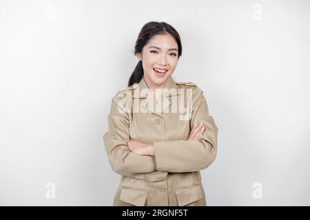 Une jeune femme asiatique en uniforme kaki brun montrant un geste confiant en pliant les bras. Fonctionnaire indonésien. Banque D'Images