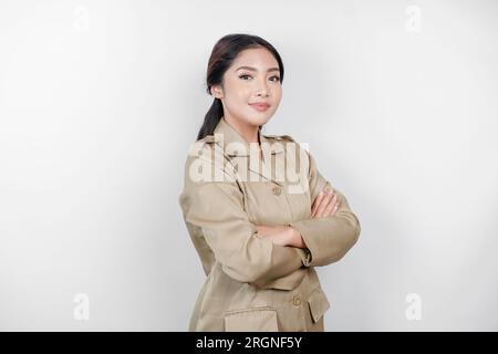 Une jeune femme asiatique en uniforme kaki brun montrant un geste confiant en pliant les bras. Fonctionnaire indonésien. Banque D'Images