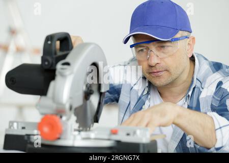 man builder utilise une scie circulaire et des lunettes de protection Banque D'Images