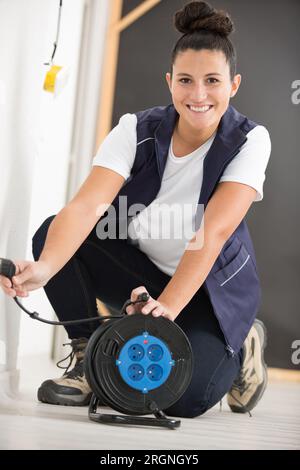 heureuse électricienne féminine travaillant sur le câblage Banque D'Images