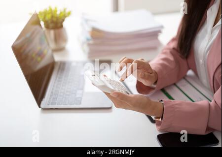 Image rapprochée d'une femme d'affaires ou d'une comptable utilisant une calculatrice à son bureau dans le bureau. Banque D'Images