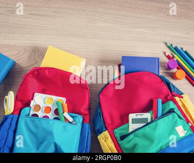 Sacs à dos colorés posés sur la table remplis de cahiers et de papeterie. Banque D'Images