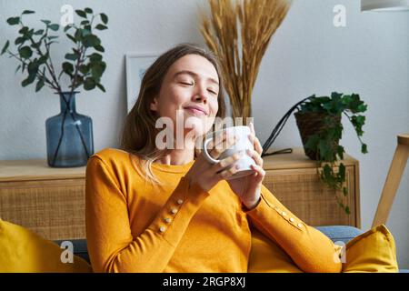 Femme détendue sentant le café le matin Banque D'Images