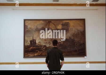 SHYMKENT, KAZAKHSTAN - 26 MARS 2023 : l'homme regarde une peinture lors d'une exposition au Musée des Beaux-Arts de Shymkent Banque D'Images