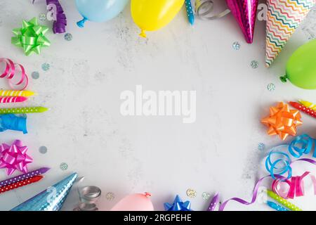 Cadre de composition plat pour fête d'anniversaire. Ballons colorés, bougies à gâteau, chapeaux de cône, arcs, décorations de rubans. Concept d'invitation avec espace de copie. Banque D'Images