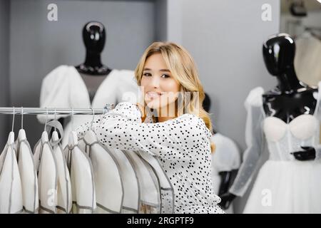 Jeune belle femme choisit une robe pour le mariage dans un salon de mariage. Banque D'Images