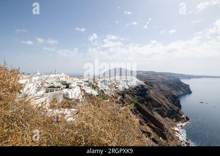 En regardant en arrière à Thera du sentier de randonnée à Oia, avec des bâtiments à travers le sommet de l'île rocheuse et la mer à droite. Banque D'Images