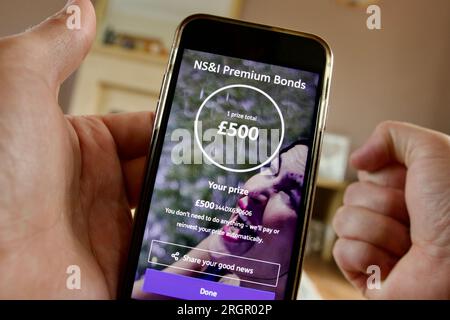 Un détenteur d'obligations Premium NS&I célèbre sa victoire après avoir révélé un prix de 500 £ sur l'application NS&I. Banque D'Images