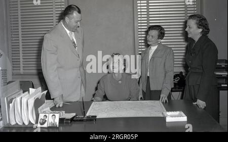 années 1950, historique, ville planning...in un bureau, un gentleman bien habillé et deux dames se tiennent à côté d'une dame assise à un bureau ayant une conversation. Une carte de la ville de Columbus, Ohio, États-Unis, est disposée sur le bureau. Columbus, l'une des rares villes des États-Unis à avoir été planifiée avant sa fondation, à partir des années 1950, a connu une croissance significative, devenant la plus grande ville de l'Ohio en terre et en population au début des années 1990 Banque D'Images