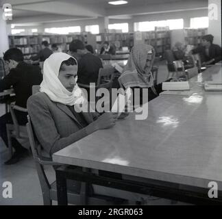 Années 1960, historique, deux hommes arabes, portant des têtes traditionnelles ou keffiyeh, assis à une table dans une bibliothèque lisant, Arabie saoudite. Banque D'Images