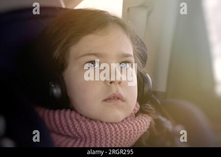 jeune fille regardant des dessins animés dans des écouteurs tout en voyageant dans une voiture Banque D'Images