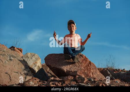 Garçon assis en méditation pose sur le rocher dans les montagnes Banque D'Images