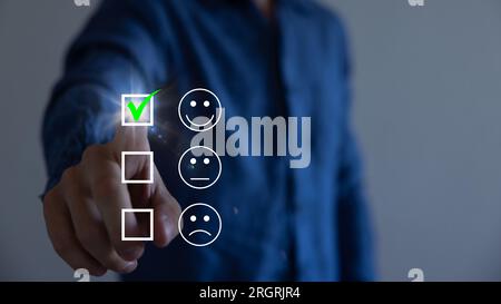 Homme d'affaires appuyant sur émoticône visage smiley sur l'écran tactile virtuel. Concept d'évaluation du service client. Banque D'Images
