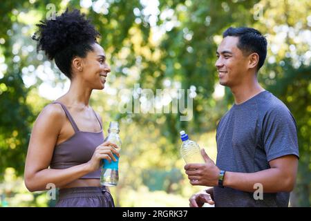 L'équipe de remise en forme se refroidit après l'exercice dans le parc, beau couple boire de l'eau Banque D'Images