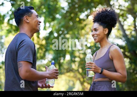 L'équipe de remise en forme se refroidit après l'exercice dans le parc, beau couple boire de l'eau Banque D'Images