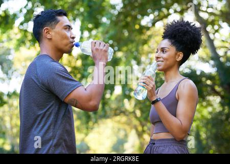 L'équipe de remise en forme se refroidit après l'exercice dans le parc, beau couple boire de l'eau Banque D'Images