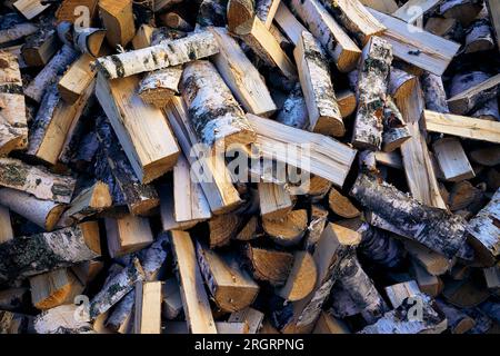 Bois de chauffage haché de bouleau empilé en pile. Clouse-up top lyer, motif, fond de buisson vert Banque D'Images