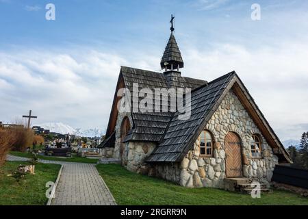 MURZASICHLE, POLOGNE - 28 AVRIL 2023 : entrée d'une petite chapelle en pierre avec une croix sur un toit dans le cimetière Murzasichle en Pologne dans les Hautes Tatras Banque D'Images