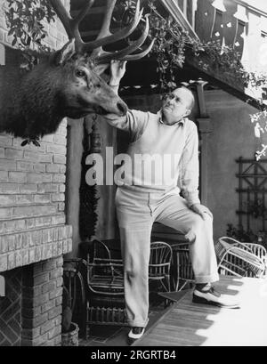 Atherton, Californie : 11 juillet 1936 la star du baseball Ty Cobb admire une tête d'élan montée sur un mur à son domicile. Banque D'Images