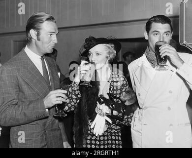 Hollywood, Californie : c. 1936 les stars de cinéma Randolph Scott, Virginia Bruce et Cary Grant profitent de boissons lors d'un événement hollywoodien. Banque D'Images
