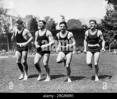 Los Angeles, Californie : c. 1927 Jack Dempsey travaille dans son jardin avec, L-R, sprinter Frank Wykoff, Dempsey, sprinter Frank Lombardi, et le champion olympique de disque de la médaille Giold, Bud Houser. Dempsey prévoit une revanche avec Gene Tunney. Banque D'Images