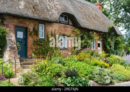 Joli chalet au toit de chaume et jardin de fleurs dans le village de Longstock, Hampshire, Angleterre, Royaume-Uni Banque D'Images