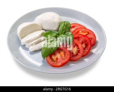 Salade Caprese faite avec des tomates fraîches tranchées, mozzarella et basilic dans une assiette isolée sur blanc avec chemin de détourage inclus Banque D'Images