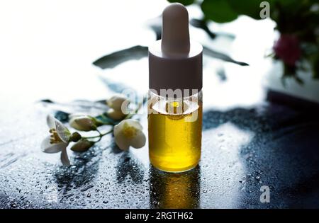 Bouteille d'acide hyaluronique avec une pipette et fleurs de printemps Banque D'Images