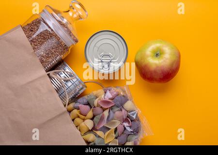 Donne des aliments en conserve sur fond de table jaune Banque D'Images