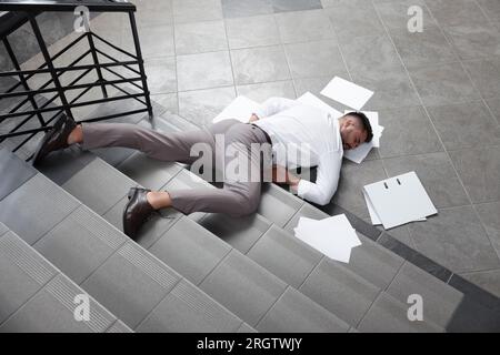 Homme Inconscient Homme inconscient avec un dossier éparpillé et des papiers couchés sur ...