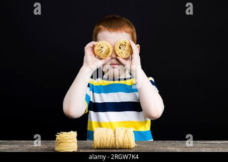 un groupe de plusieurs portions de vraies nouilles à la farine de blé tordues en forme de nid, un garçon joue et prépare des pâtes Banque D'Images