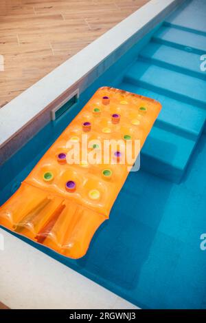 Matelas gonflable orange dans la piscine. Summertime Banque D'Images