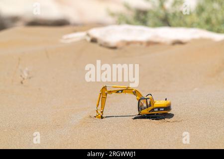 Excavatrice modèle jouet Caterpillar sur le sable dans le désert Banque D'Images