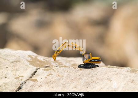 Excavatrice modèle jouet Caterpillar sur le sable dans le désert Banque D'Images