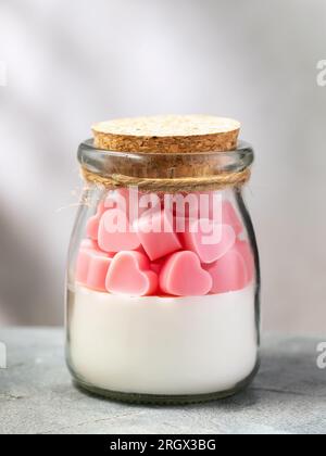 Bougie parfumée avec parfum de vanille et de baies dans un bocal en verre transparent sur la table Banque D'Images