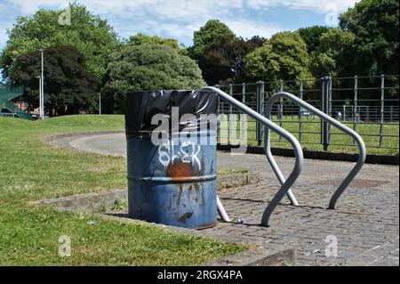 Poubelle et hangar à vélo dans le parc. Un baril métallique comme poubelle. Banque D'Images