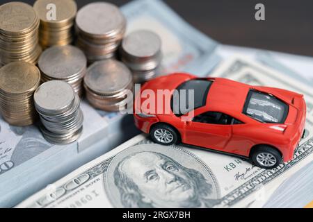 Modèle de voiture miniature et état financier avec pièces de monnaie. Financement et prêt de voiture, économiser de l'argent pour un concept de voiture. Prêt automobile, argent, billet de banque sur accord Banque D'Images